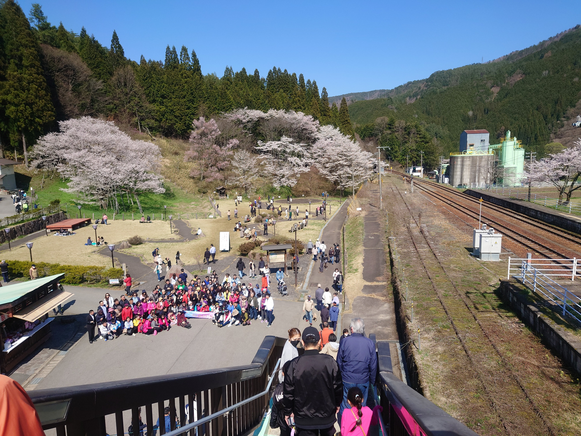 「JR飛騨一ノ宮駅」から「臥龍公園」へと通じる連絡通路から見た風景。集合写真を撮影している人だかりの背後に蓋があります。